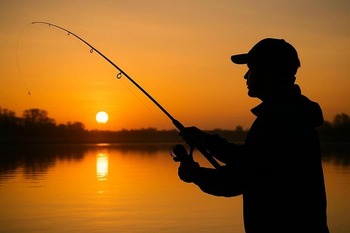 Angler silhouette lining up a cast at sunrise